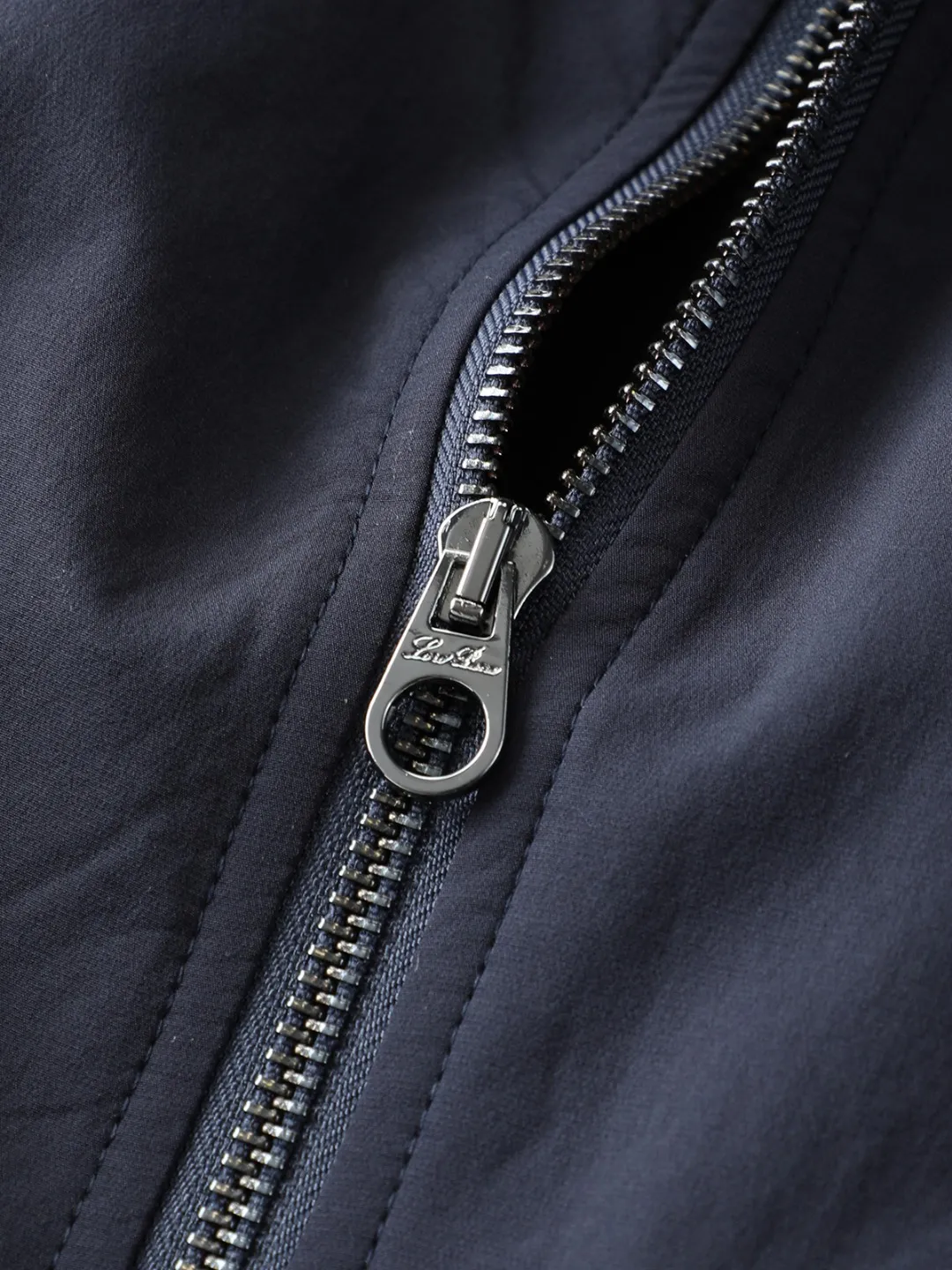 Loro Piana LP Men's Pilot Lapel Thin Cotton Jacket LP Pilot Style Cotton Jacket with Stand-up or Lapel Collar: A great choice for autumn and winter when you need both warmth and elegance. The weather has turned cooler recently. Are you looking for a jacket that is both warm and not bulky? LP's pilot cotton coat may be the answer. It uses 86.7% nylon + 13.3% cotton spandex four-way stretch fabric, and is filled with 60 g/m² of high-quality thermal insulation cotton to perfectly integrate the two seemingly contradictory needs of warmth and slimming. The first thing I felt when I put it on was "the elasticity is so good." The high-elastic fabric allows unrestricted movement, making it easy to lift your hands and turn around. The thermal insulation cotton inside is filled just right. It is not as fluffy as a down jacket, but it can effectively lock in body temperature. It is an ideal choice for weather conditions around 10℃. The thickness is controlled very smartly, so it can withstand the autumn wind when worn alone. Even if it gets colder, there is no pressure to wear it with a sweater underneath. The most surprising thing about this jacket is its ability to "transform". The 12-needle threaded knitted collar can be switched between stand-up collar and lapel modes at will. When the weather is cold, stand up the collar to keep warm, and when the temperature rises, turn down the collar for casual wear. The No. 5 resin double zipper design makes it particularly convenient to put on and take off. The zipper puller and zipper piece have been processed in the same color. From a distance, the existence of the zipper is almost invisible. This kind of control over details is really rare. The vertical zipper pockets on the chest adopt double pocket lip technology, which not only ensures practicality, but also allows the pockets to perfectly integrate into the overall lines of the clothes. The most amazing thing is the grid processing of the pocket flap and the body. This process requires more fabrics and man-hours, but the final effect is really worth it. It looks seamless from a distance, but only when you look up close can you see the carefully designed details. The cuffs and hem are made of the same 12-needle mercerized cotton thread as the collar. It has moderate elasticity without being tight, and the windproof performance is not compromised at all. The slightly wide silhouette is friendly to all body types, and the one-piece back design allows for more freedom of movement. The solid color smooth lining inside is skin-friendly and breathable, making it particularly smooth to put on and take off. The color Navy Blue is chosen just right, not too boring but still Versatile enough. Paired with casual pants, it is the perfect choice for going out on the weekends. Paired with slim-fitting trousers, it can easily cope with business and leisure occasions. Best of all, this jacket requires almost no special care and stays crisp and stylish once you hang it. This bomber jacket understands the pace of modern life best. It knows we need pieces that can handle formal occasions yet remain comfortable in everyday life. Those well-designed threaded necklines, color-matching zippers, and hidden pockets all silently enhance the wearing experience. It is not the kind of clothing that relies on exaggerated design to attract attention, but impresses you with real comfort and practicality. Color: Blue Black Size 48-56